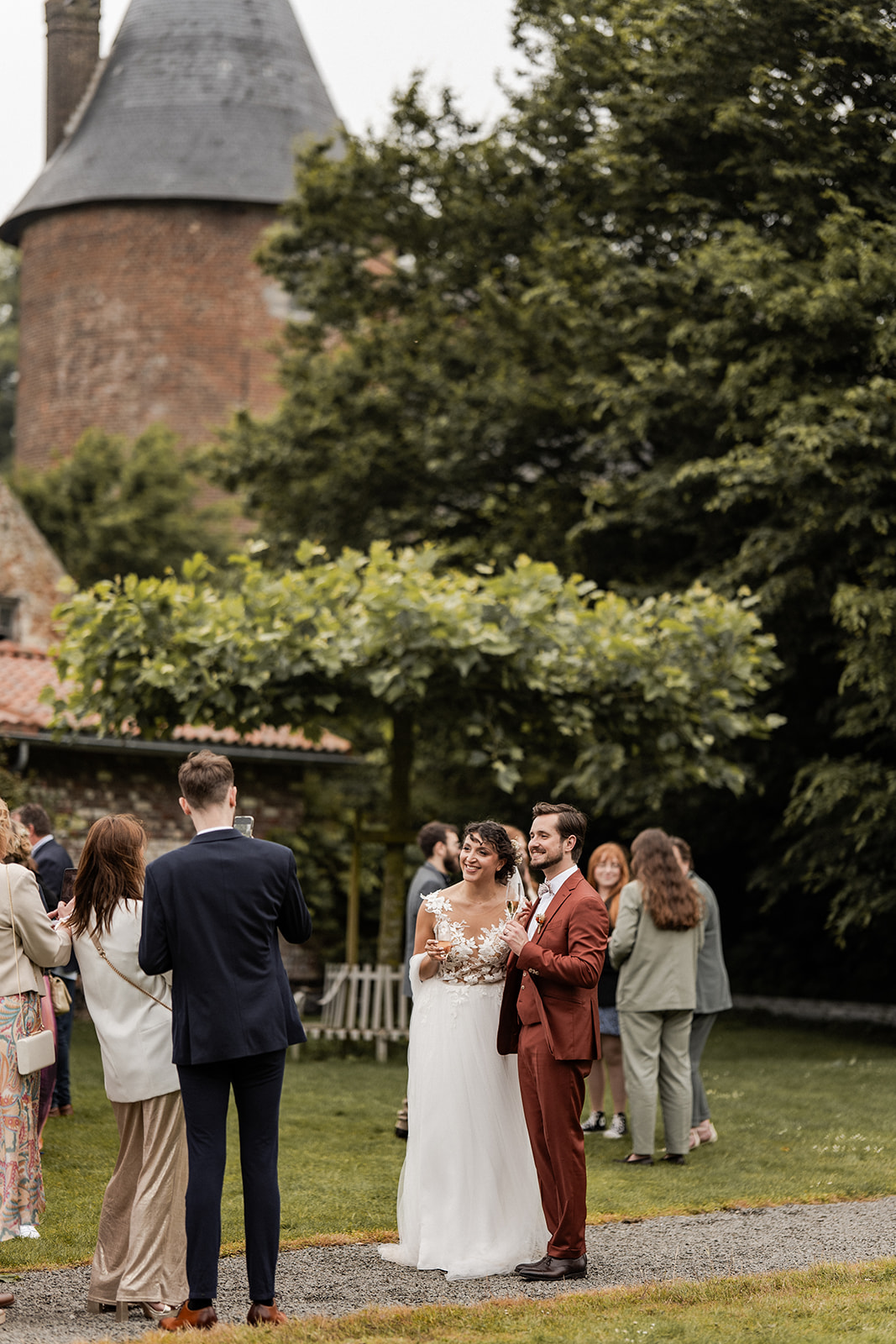 Photographie d'un couple de mariés lors du vin d'honneur de leur mariage, dans le jardin de La Cense d’Abaumont en Belgique
