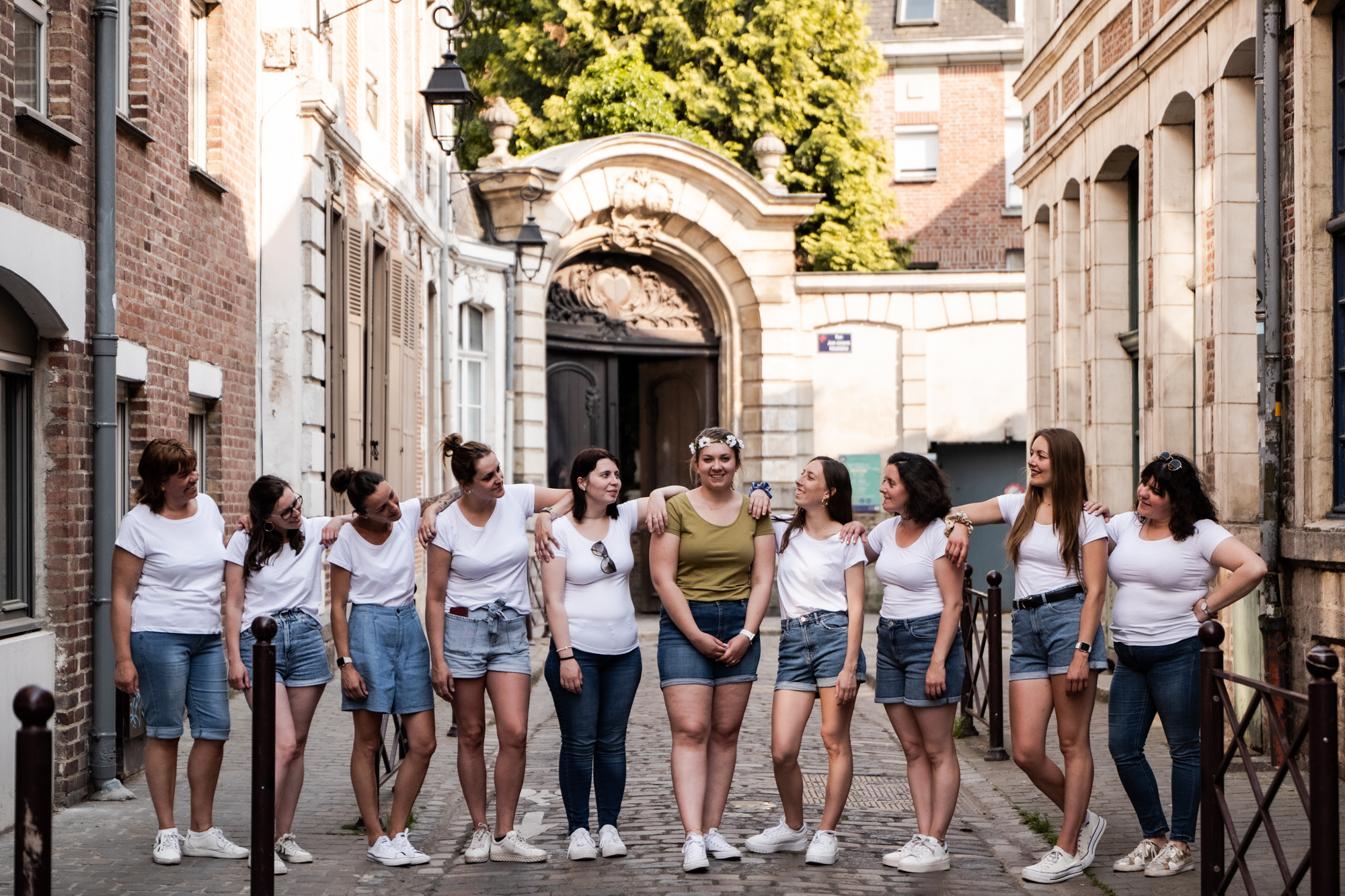 Photographie d'un groupe d'amies alignées toutes avec un t shirt blanc dans une ruelle du Vieux Lille lors d'un EVJF