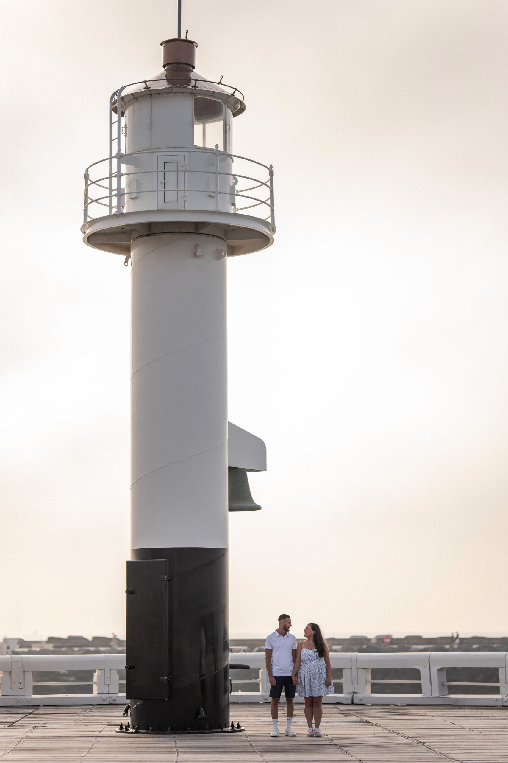 Photographie d'un couple de futurs mariés sur le ponton du phare de la plage d'Ostende lors d'une séance photo couple