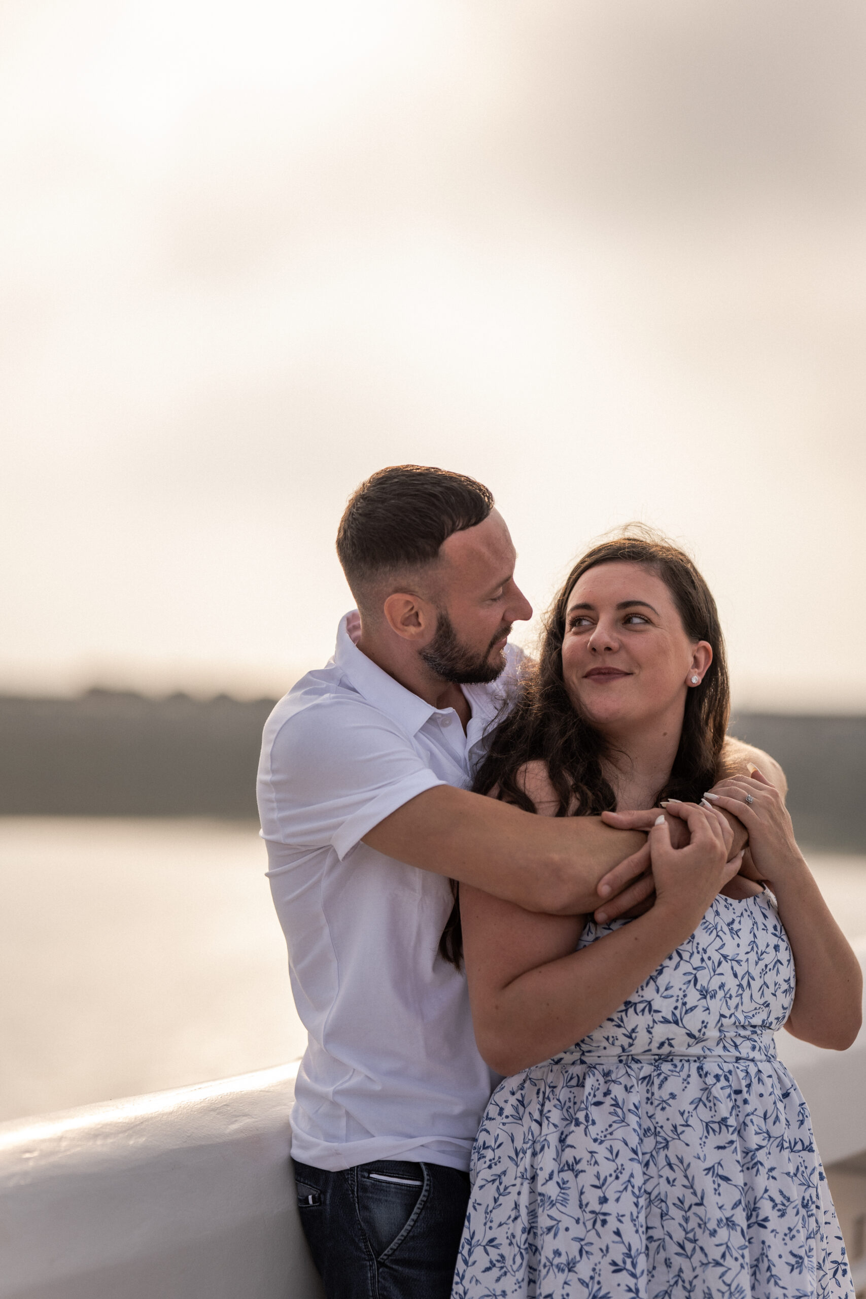 Photographie d'un couple de futurs mariés enlacés dans les bras l'un de l'autre et se regardant sur le ponton de la plage d'Ostende lors d'une séance photo couple