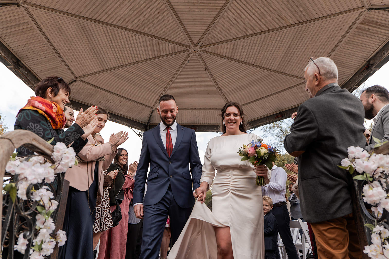 Photographie d'un couple de mariés sortant de leur cérémonie civile entourés de leurs invités qui les applaudissent lors de leur mariage à Ostende en Belgique