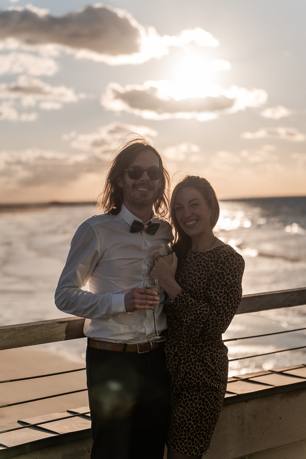 Photographie d'un couple enlacer et tenant une coupe de champagne sur la terrasse du Pier de Blankenberge lors d'un vin d'honneur d'un mariage